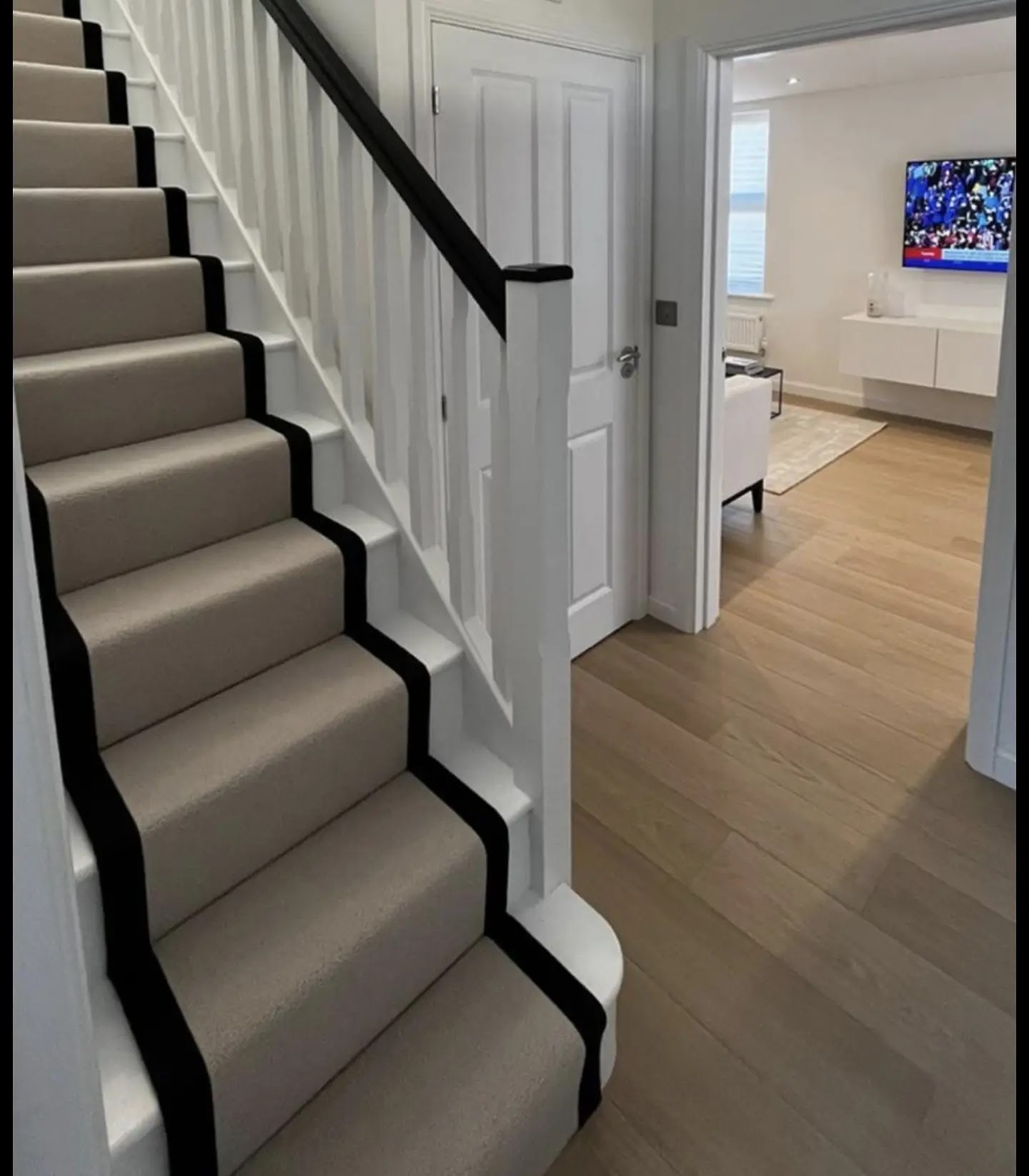 Stair carpet with black borders above a wood-effect hall floor