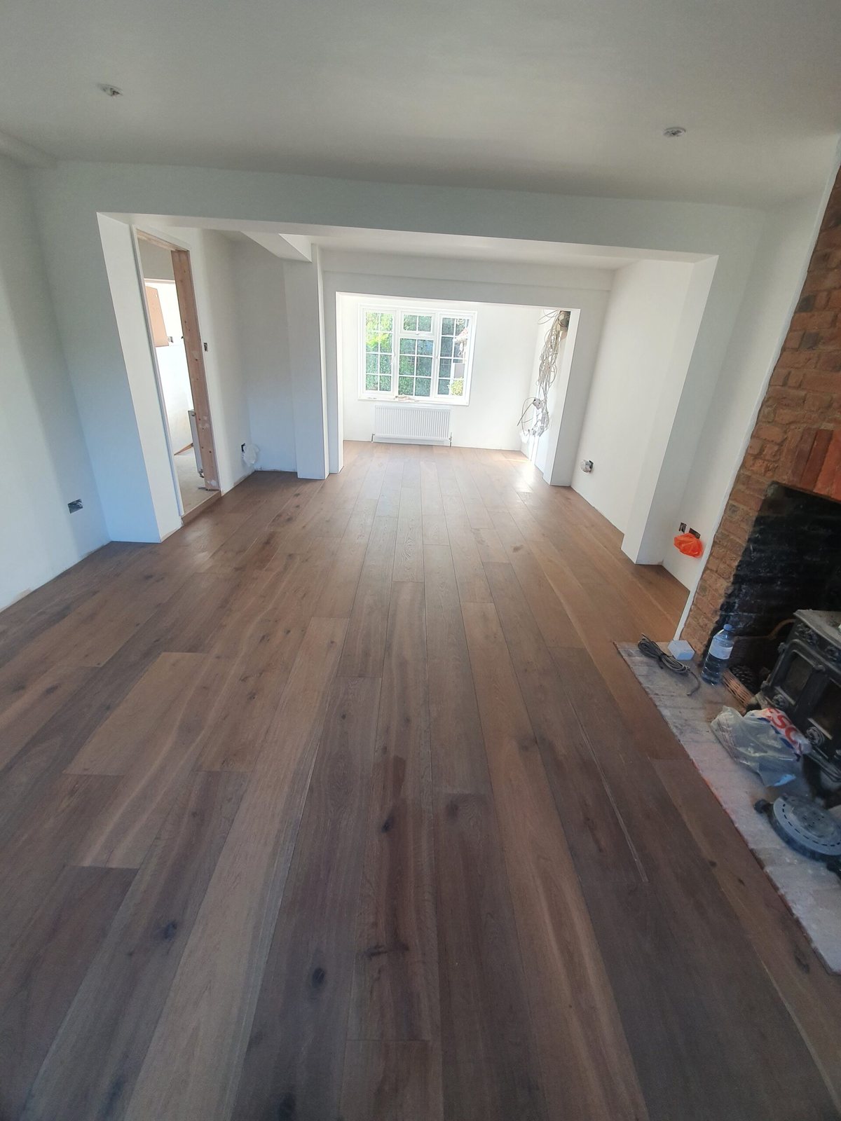 Wood-effect plank floor through a through-lounge with a brick fireplace