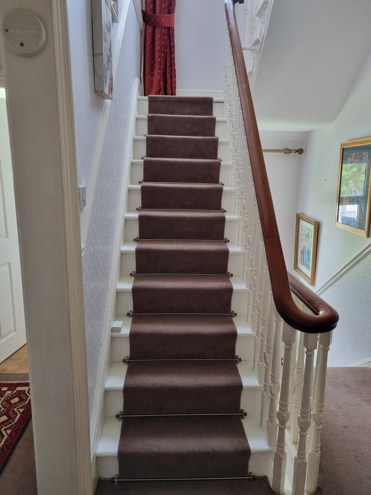Dark carpet runner fitted up a white staircase