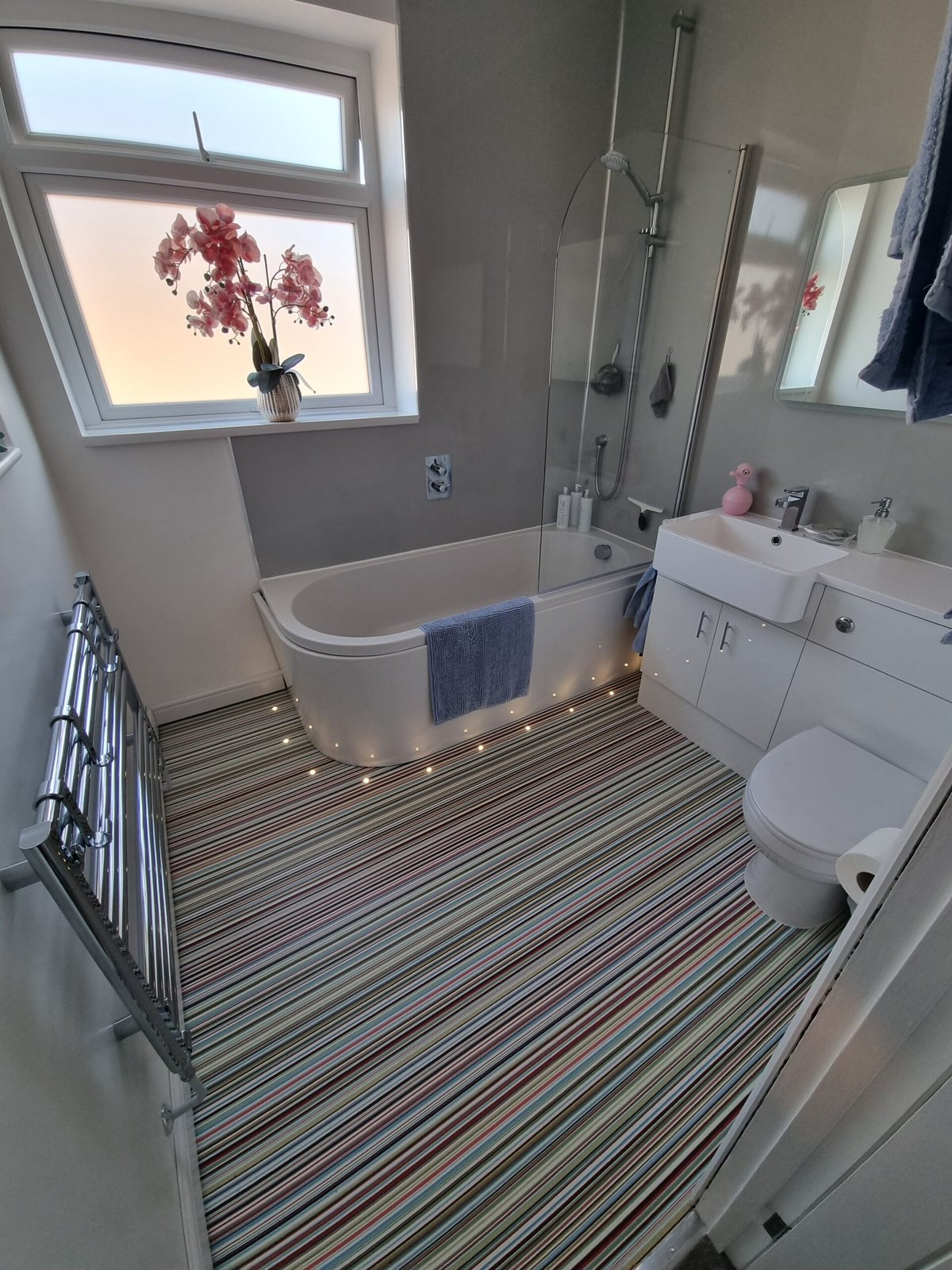 Bathroom with a multicolour striped floor and a freestanding bath