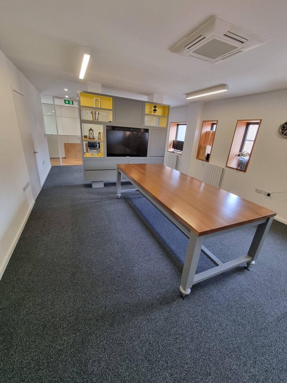 Office with grey carpet tiles under a long meeting table