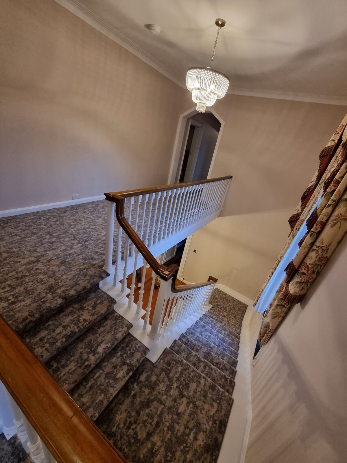 Patterned carpet on a staircase and landing under a chandelier