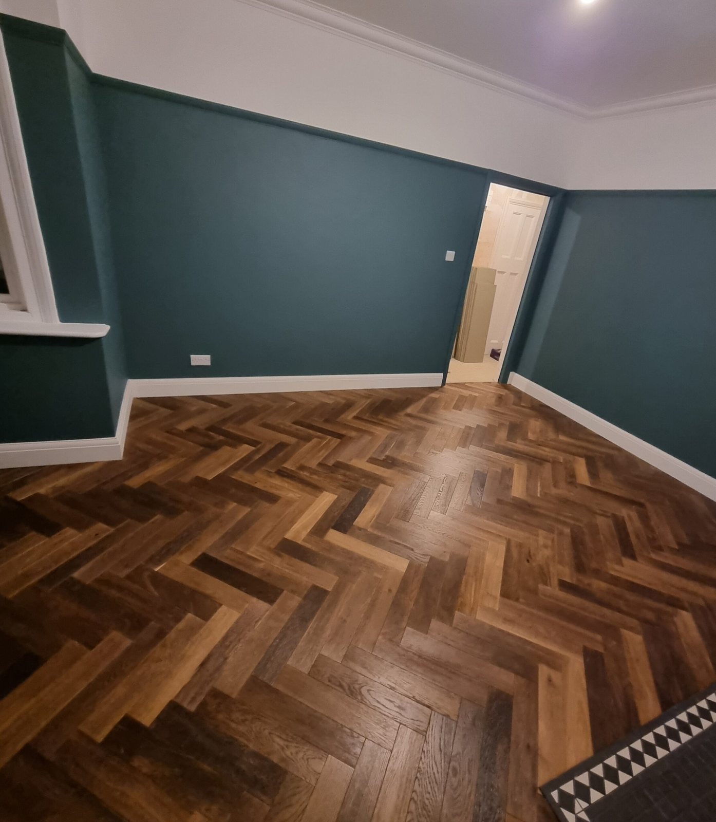 Dark herringbone floor in a teal-walled room