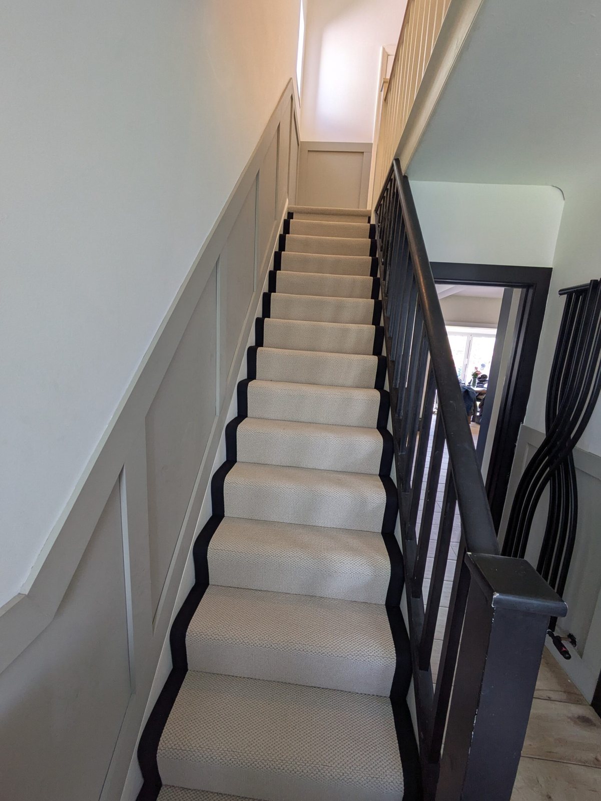 Cream stair runner with black borders fitted up a panelled staircase