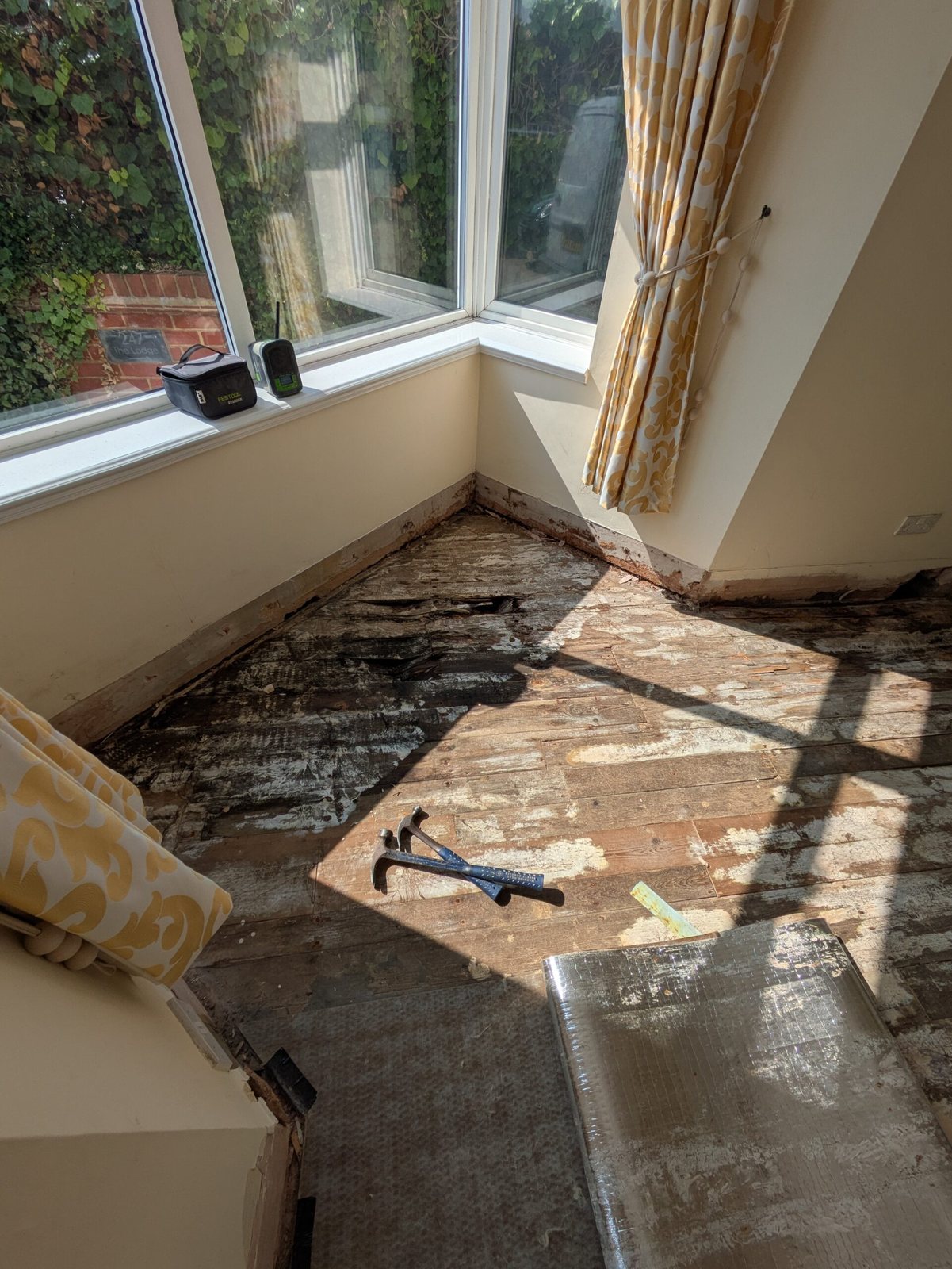 An old floor being lifted in a bay-window room before new flooring